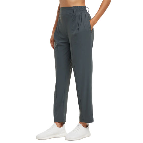 A person wearing dark gray jogger pants with an elastic waistband and pockets, paired with white sneakers.