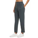 A person wearing dark gray jogger pants with an elastic waistband and pockets, paired with white sneakers.