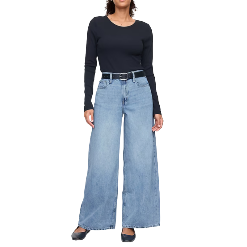 Mid-rise, drapey soft baggy jeans in light blue denim, featuring a wide-leg fit and subtle fading. Paired with a black long-sleeve top, black belt, and black flats.