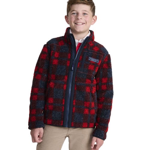 A young person is wearing a plaid fleece jacket in red and black with a high collar and front zip.