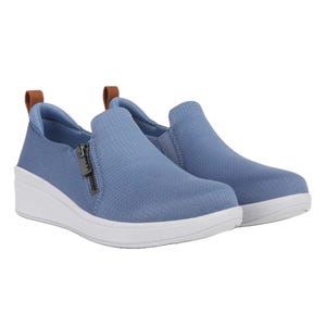 Light blue slip-on sneakers with a white platform sole and side zippers for easy wear, featuring a brown pull tab at the back for convenience.