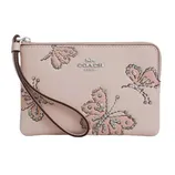 A beige wristlet from Coach featuring butterfly embroidery and stud embellishments, with a detachable wrist strap.