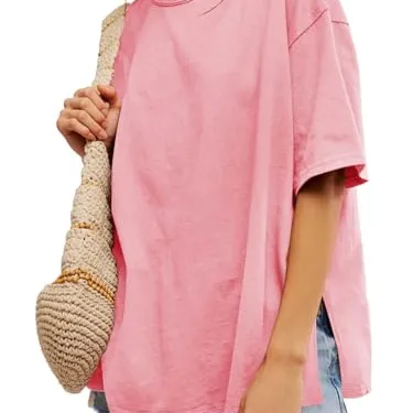 A person wears a loose-fitting pink T-shirt, denim shorts, and carries a woven bag.