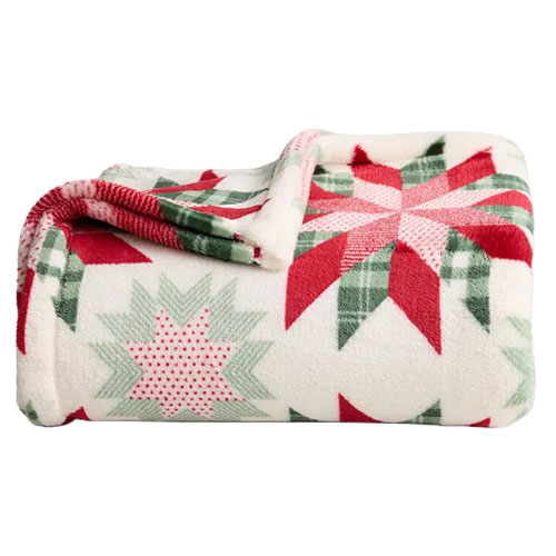 A soft fleece blanket with a red, green, and white festive star pattern, perfect for a cozy winter setting.