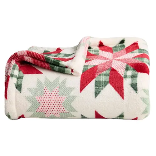 A soft fleece blanket with a red, green, and white festive star pattern, perfect for a cozy winter setting.
