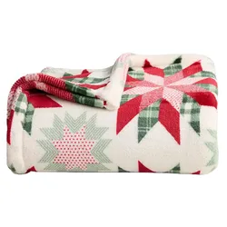 A soft fleece blanket with a red, green, and white festive star pattern, perfect for a cozy winter setting.