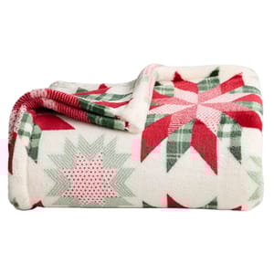 A soft fleece blanket with a red, green, and white festive star pattern, perfect for a cozy winter setting.