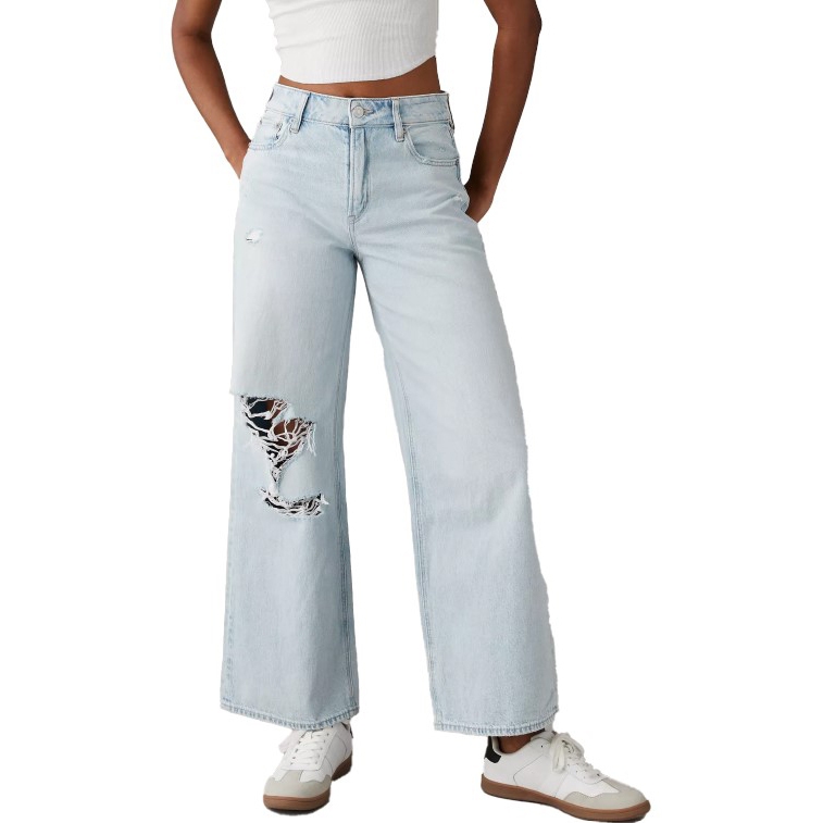 Light wash high-waisted jeans with a relaxed fit, featuring a distressed detail on one leg. The jeans are paired with white sneakers.