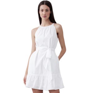 White sleeveless mini dress with a halter neckline, cinched waist with a bow tie, and a tiered ruffle hem, crafted from poplin fabric.