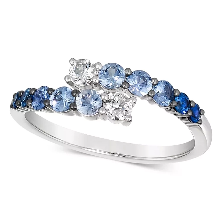 A ring with a curved band, featuring a gradient of blue sapphires set in white metal, flanked by round white gemstones.