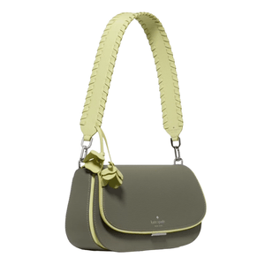 A small green crossbody bag with a wide, braided shoulder strap and floral charms, featuring the \“kate spade new york\“ logo.