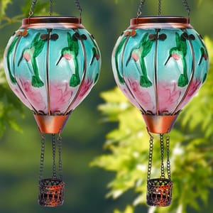 Two decorative, colorful hot air balloon-shaped solar lanterns with floral and hummingbird designs, featuring intricate metal baskets hanging below.