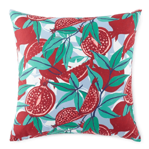 Decorative pillow featuring a colorful pattern of red pomegranates and green leaves on a light blue background.