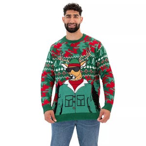 An ugly Christmas sweater featuring a cartoon deer with sunglasses and a green suit, set against a green and red camo pattern with white and green diamond accents.