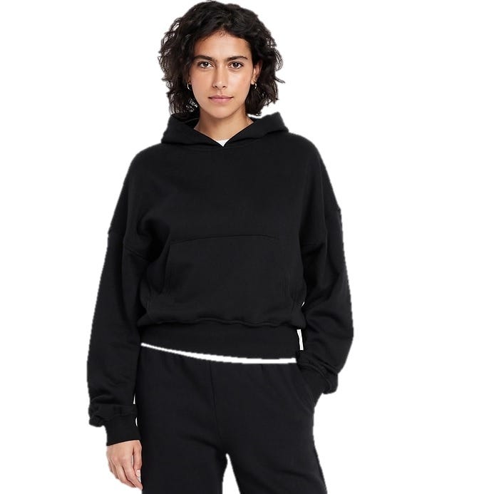 A person wearing a black hoodie with a front pocket and black pants, posing against a white background.