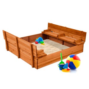 47\“ cedar sandbox with built-in benches, filled with sand, includes toy accessories like a colorful beach ball, bucket, shovel, and star mold. The benches fold down for covering the sandbox when not in use.