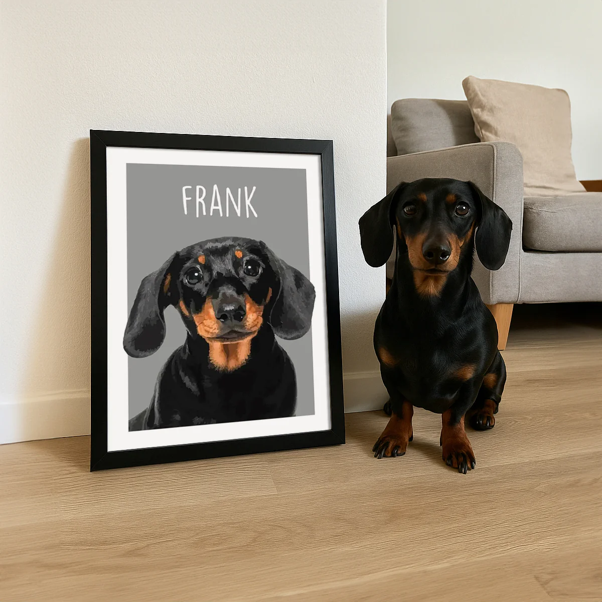 A Dachshund sits beside a framed illustration of itself labeled \“FRANK\“ in large white letters, placed on the floor in a living room setting.