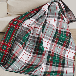 A multicolored plaid throw blanket is draped over the arm of a beige sofa.