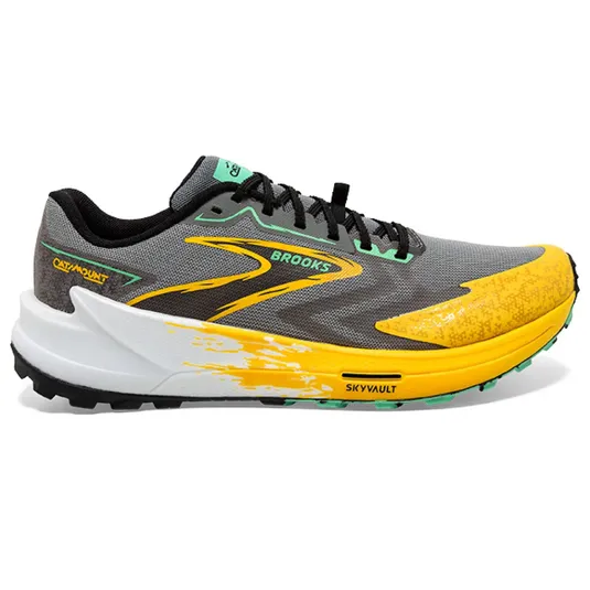 Brooks Catamount Skyvault trail running shoe features a gray upper with yellow and green accents, a cushioned white midsole, and a grippy black outsole.
