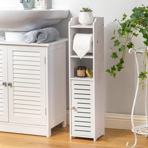 White, narrow bathroom storage cabinet with a top shelf for a small plant, a middle shelf with toilet paper, and a lower compartment with a door. It stands next to a sink cabinet, ideal for compact storage solutions. 30\“ tall.
