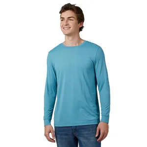 A man is wearing a light blue long-sleeve shirt made from breathable, moisture-wicking mesh fabric. The shirt has a simple design and pairs with jeans for a casual look.