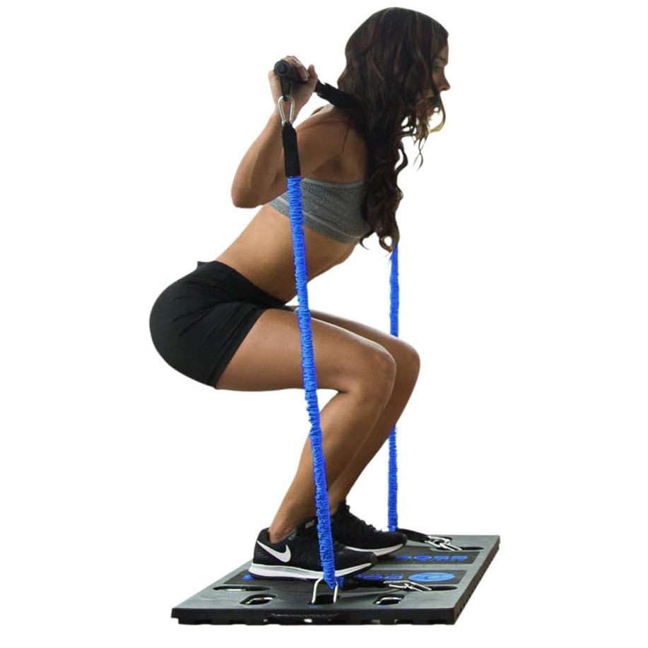 A woman performs squats using a portable home gym comprising a resistance band set and a sturdy platform, which provides resistance for various exercises.