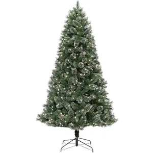 A pre-lit artificial Christmas tree with a metal stand, featuring green branches dusted with snow and integrated warm white lights.