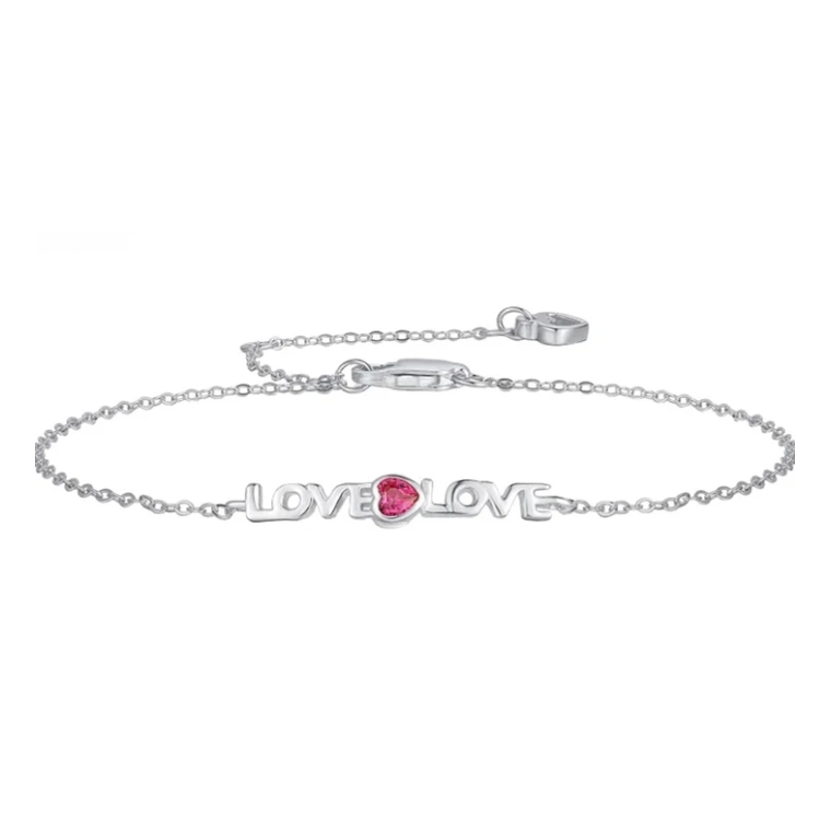 A delicate silver chain bracelet features the word \“LOVE\“ repeated twice, with a small pink heart-shaped gemstone in the center. It includes a lobster claw clasp for fastening.
