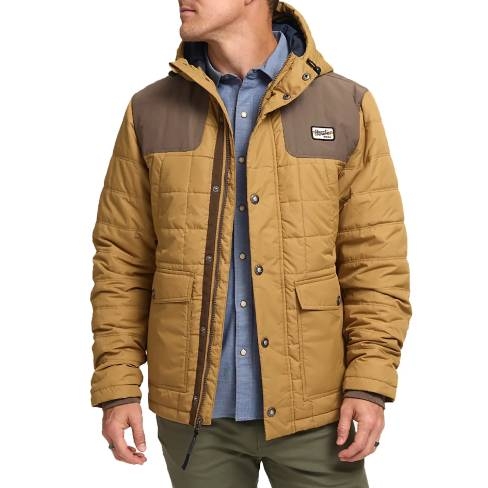 The Howler Brothers Spellbinder Parka is a quilted jacket in tan with a brown yoke and a hood. It features front pockets and a snap-button closure, paired with a blue inner shirt and olive pants.