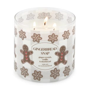 Gingerbread Snap scented candle with three wicks, featuring ginger crystals, vanilla, and shortbread notes. Decorated with gingerbread and snowflake designs.