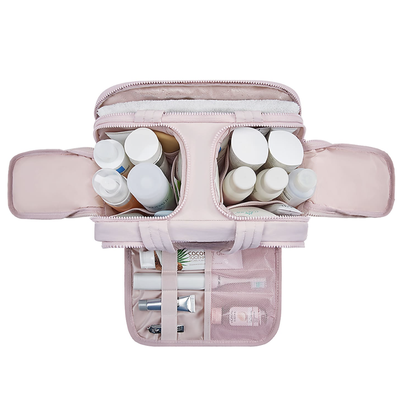 A pink toiletry organizer is open, displaying various travel-sized bottles of personal care products, tubes, and a toothbrush in compartments and mesh pockets.