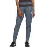 A person wearing gray Adidas track pants with white stripes and black Adidas shoes.