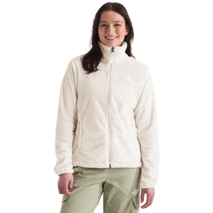 A woman is wearing a cream-colored fleece jacket with a full zipper and high collar, paired with light green cargo pants.