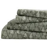 A stack of bedsheets with a forest tree pattern in white on a dark green background.