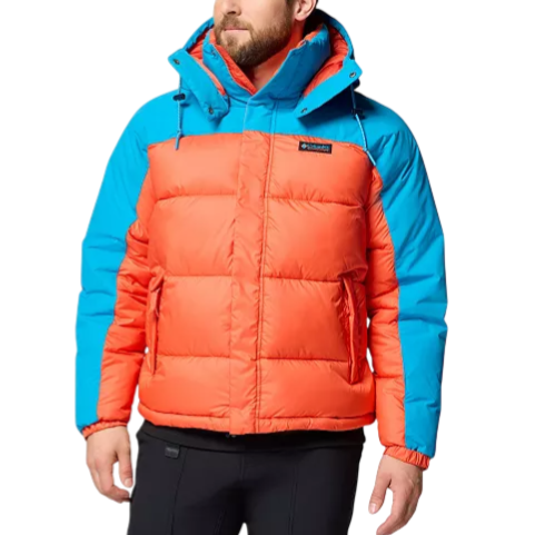 A man wears a two-tone puffer jacket with an orange body and blue shoulders, featuring a hood and black pants.