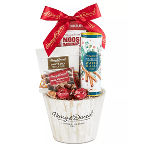 The Harry & David gift basket includes Moose Munch, sweet and spicy snack mix, milk chocolate truffles, hazelnut wafer rolls, all packaged in a branded bucket with a red ribbon.