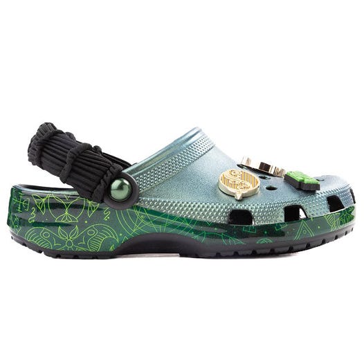 A pair of Crocs featuring a futuristic design in metallic green with scientific symbols, accessorized with embellishments and a black strap.