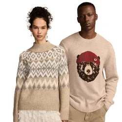 A woman and a man are wearing beige sweaters; hers features a geometric pattern, and his has a bear design with a red hat.