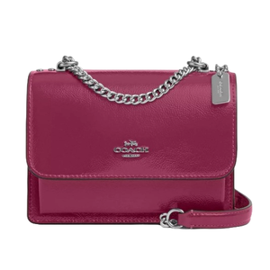 A maroon Coach Outlet Leather Mini Crossbody with a sleek design, featuring a silver chain strap, flap closure, and a small Coach logo on the front.