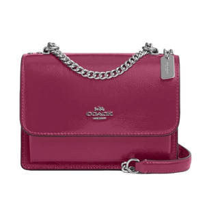 A maroon Coach Outlet Leather Mini Crossbody with a sleek design, featuring a silver chain strap, flap closure, and a small Coach logo on the front.