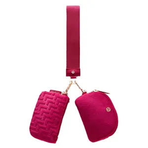 Magenta crossbody bag with two zippered pouches, one featuring a textured pattern. The strap connects to the pouches with gold hardware.