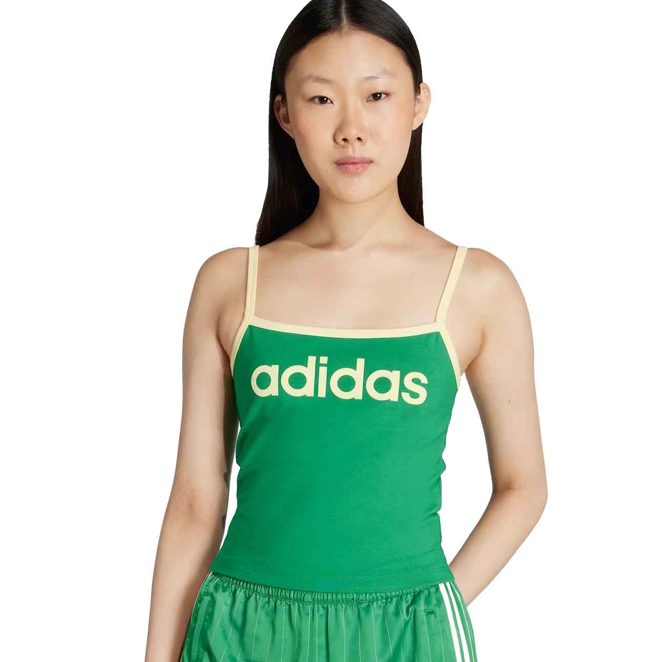 A person wearing a green Adidas tank top with yellow straps and the brand logo on the front, paired with matching green shorts featuring white stripes.