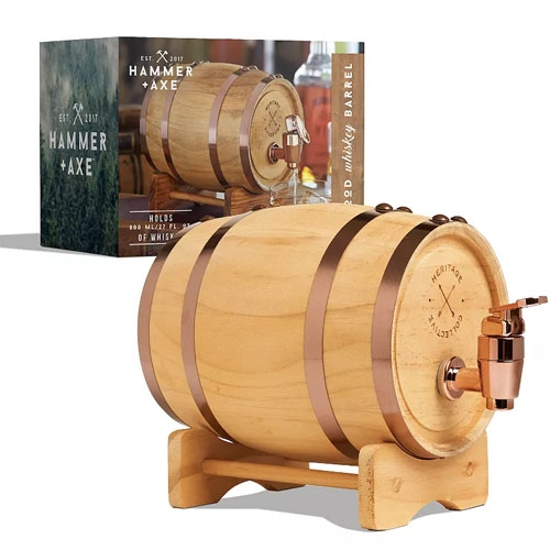 A 1L mini whiskey barrel made of wood with copper accents, featuring a tap for dispensing and a sturdy stand. The packaging displays the same barrel, labeled \“Hammer + Axe,\“ with a focus on personalized whiskey aging.