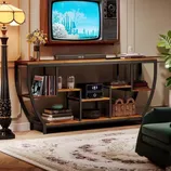 A vintage television set is mounted above a console table with shelves, holding vinyl records, a radio, and decorative items, flanked by a floor lamp and a patterned rug in a stylish living room setup.