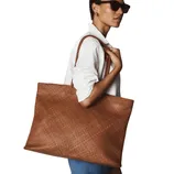 A person wearing a white shirt and sunglasses carries a large, woven brown tote bag on their shoulder.