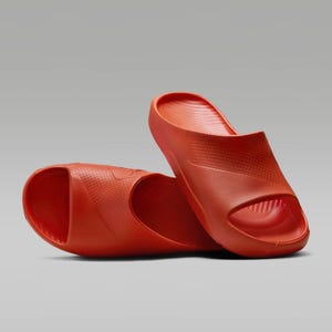 A pair of red slide sandals with a textured design.