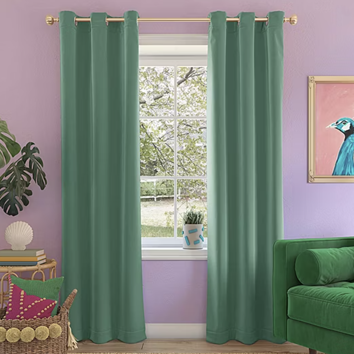 A teal energy-saving blackout curtain panel hangs from a gold rod against a lavender wall, effectively blocking light. It complements the room's decor, which includes a green couch, potted plant, and vibrant pillows.