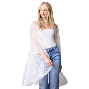 A woman is wearing a white, sheer lace kimono over a white top, paired with blue jeans.