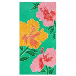 A colorful beach towel featuring large floral designs with yellow and pink hibiscus flowers on a green background.