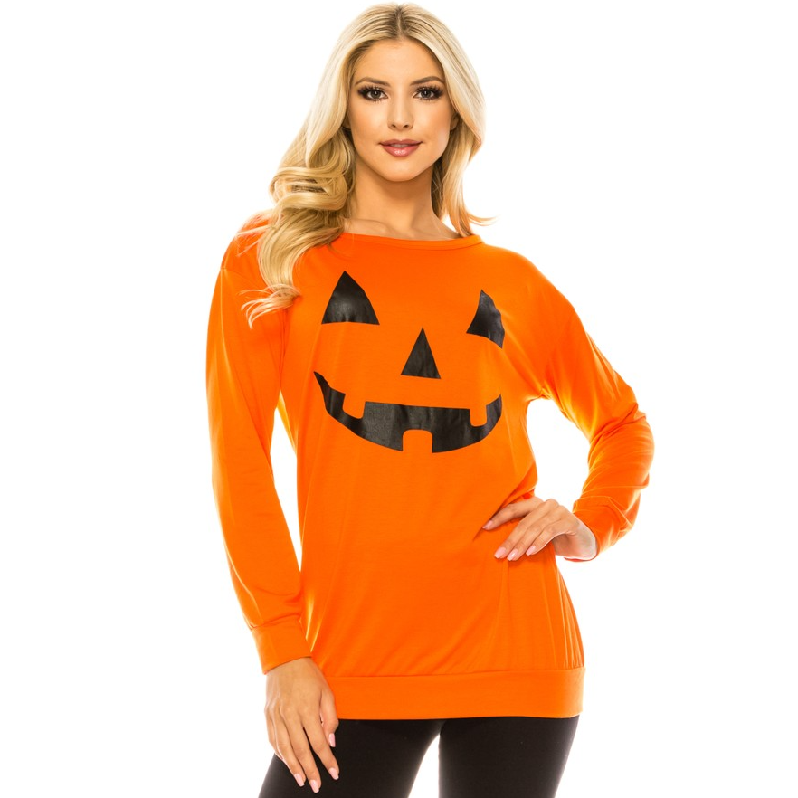 A woman is wearing an orange long-sleeve shirt with a black jack-o'-lantern face design, paired with black leggings.
